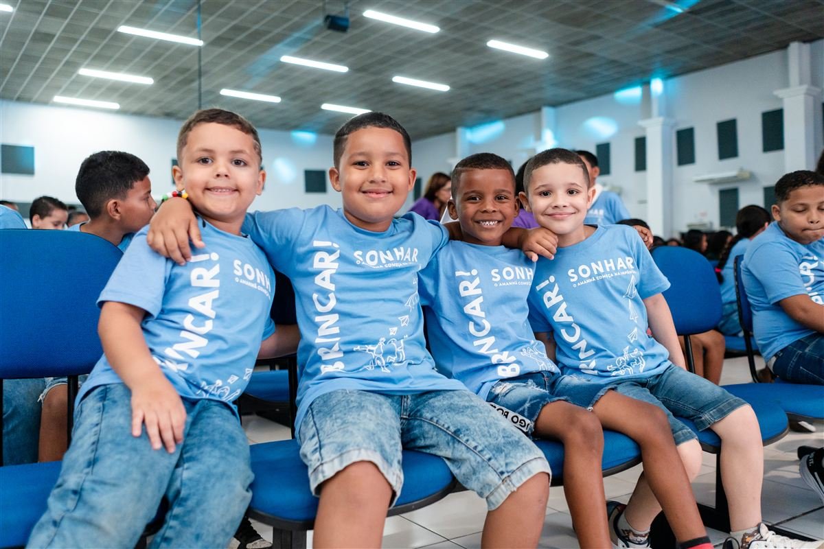 Crianças do SCFV do Instituto Alfa reunidas em evento institucional vestindo camisetas da campanha 'Brincar, Sonhar'.